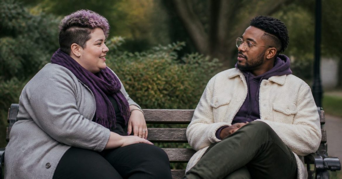Two adults having a comfortable, thoughtful conversation on a park bench